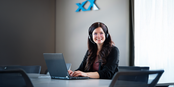 Eine Vertriebsmitarbeiterin mit Headset sitzt am Laptop im SUXXEED Büro