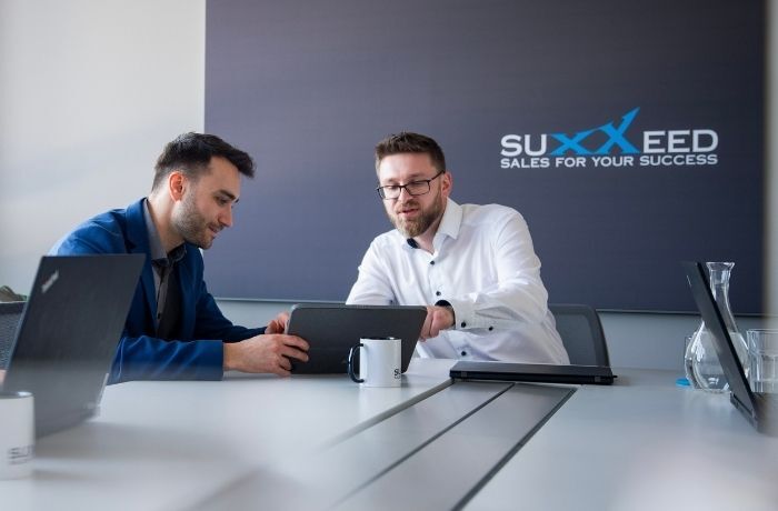 Sales Manager im Kundengespräch in einem modernen Meetingraum bei SUXXEED