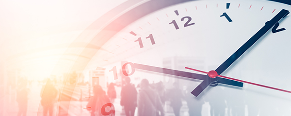 Analoge Uhr im Vordergrund, Menschen im Hintergrund – Symbol für Arbeitszeit